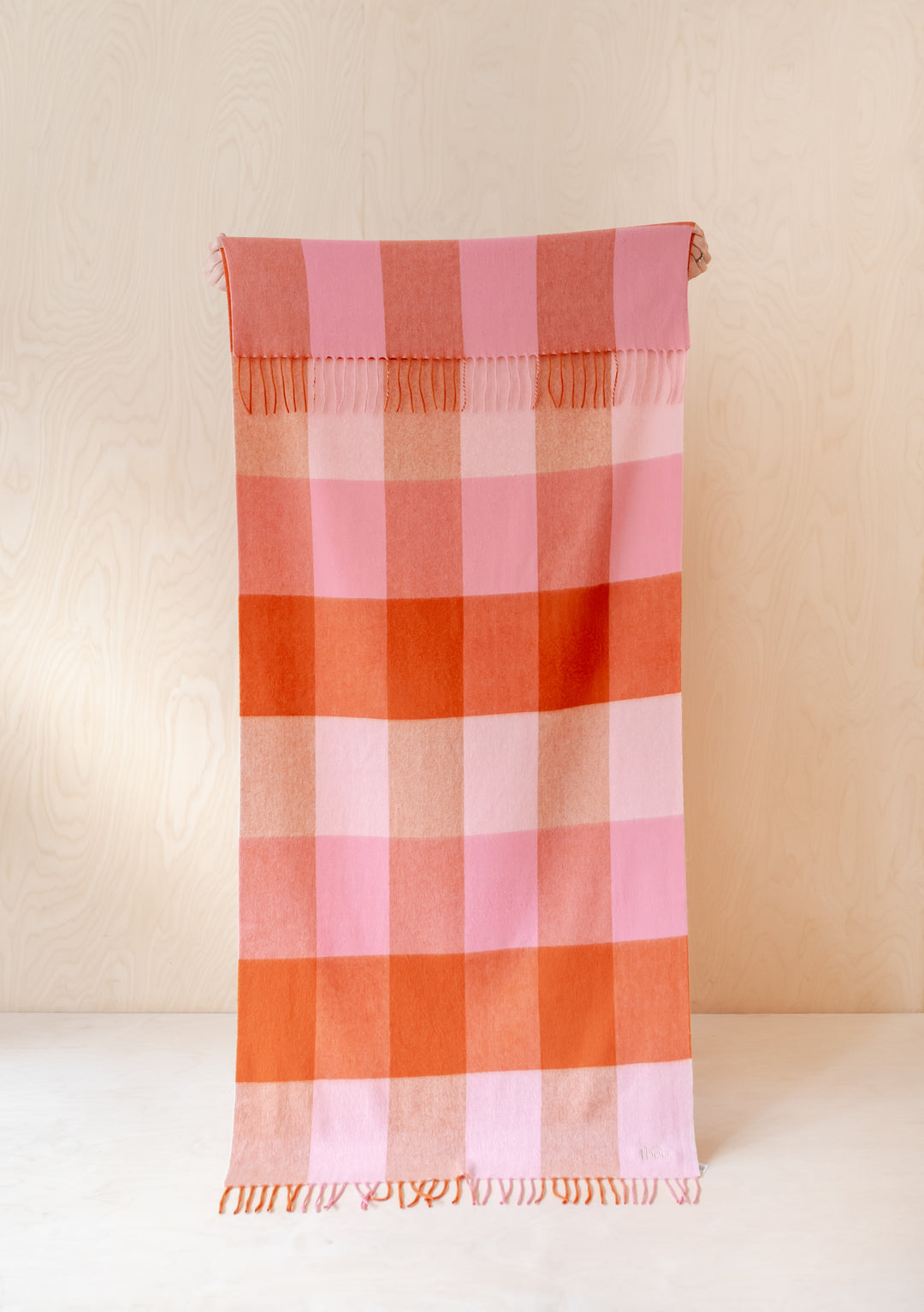 TBCo Lambswool Kids Blanket in Blush Grid Check displayed flat showing pink and rust checkered pattern with fringed edges