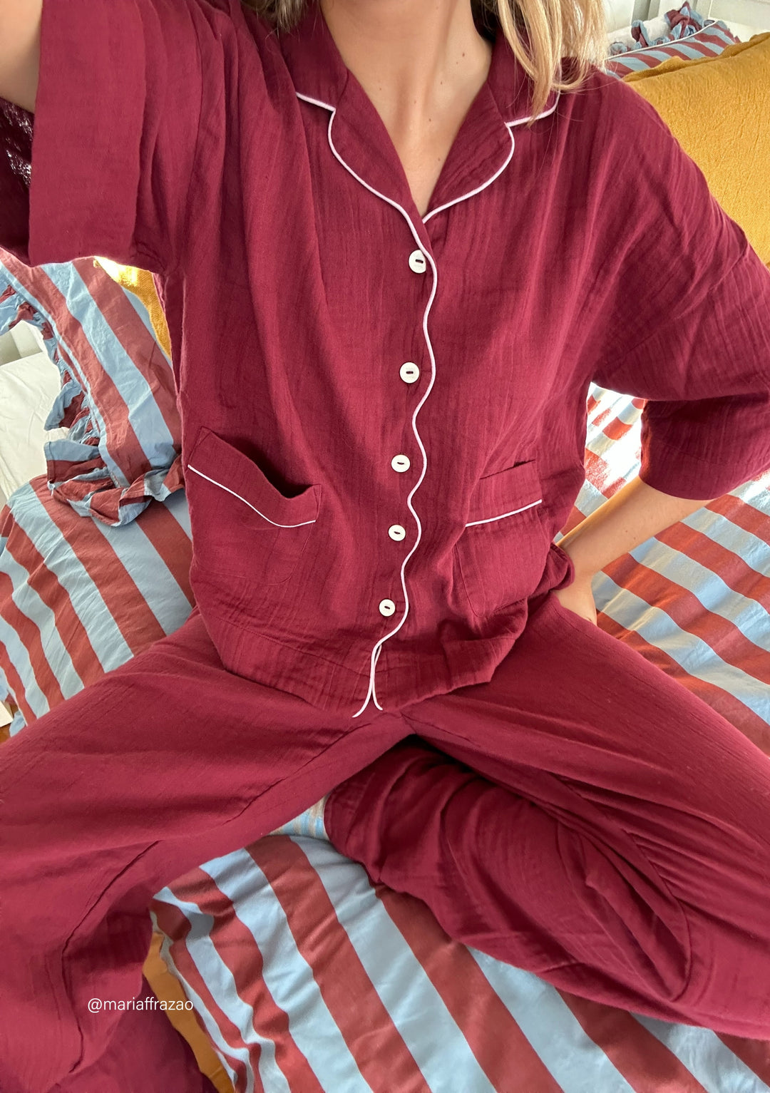 TBCo Cotton Pyjamas in burgundy with white piping detail, front button closure and patch pockets against striped bedding