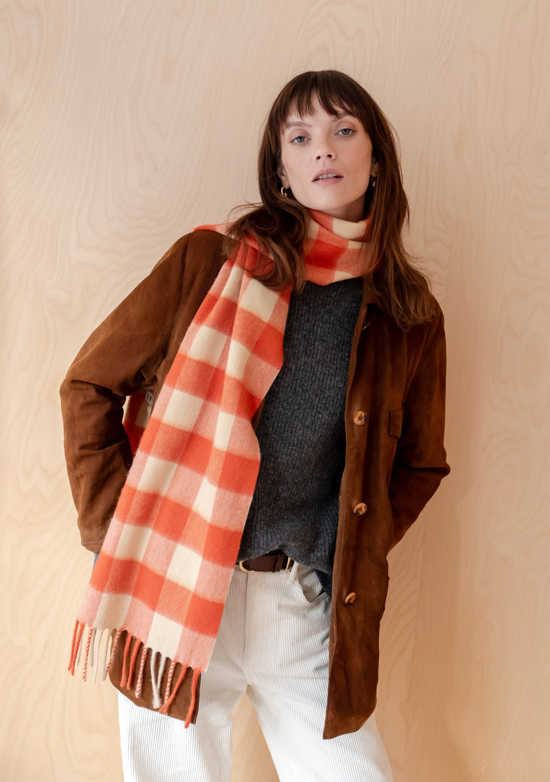 Orange and cream gingham lambswool TBCo scarf draped stylishly with brown jacket and grey jumper in lifestyle product photo